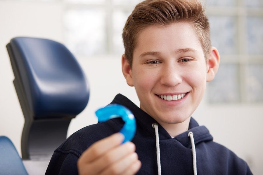 Ein Jugendlicher zeigt lachend seine blaue Zahnspange.