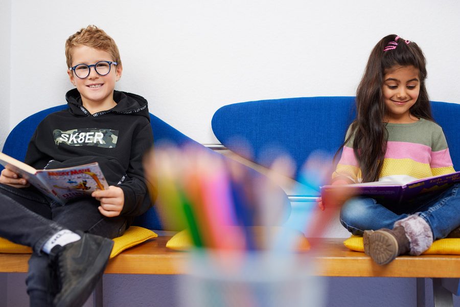 Zwei Kinder lesen im Wartebereich der Praxis.
