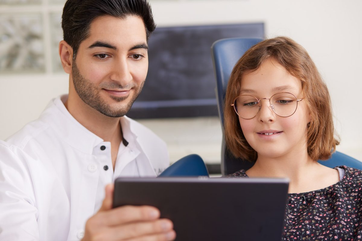 Niaz Daniel Alavi zeigt einer jungen Patientin Aufnahmen auf einem Tablet.